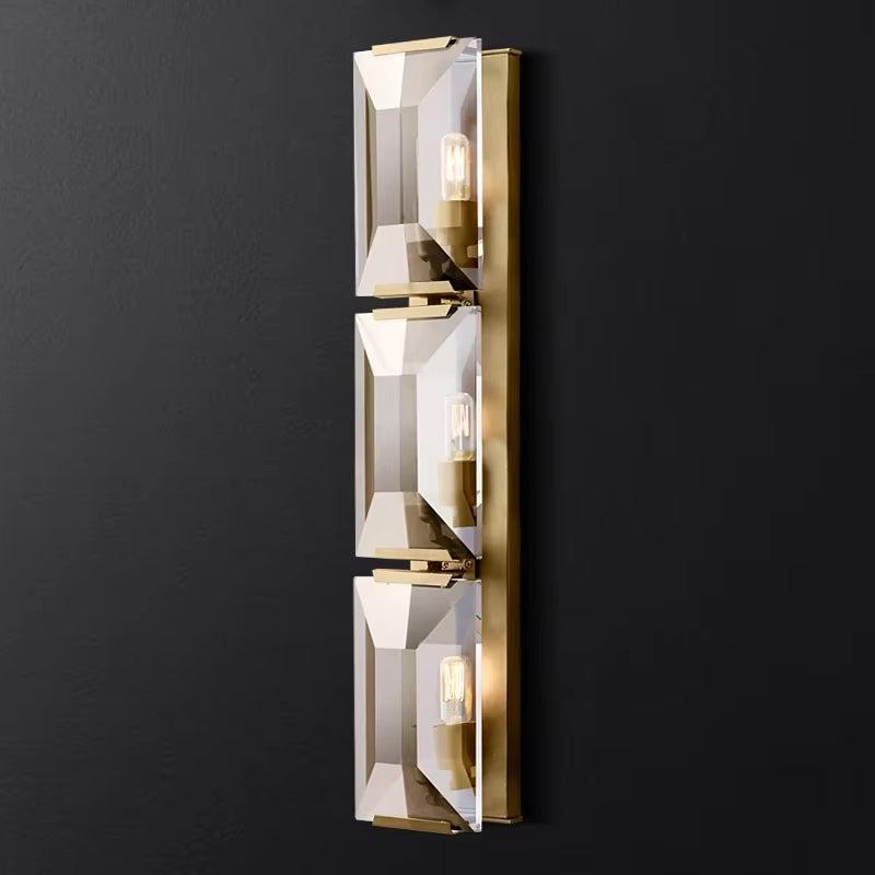 Modern crystal wall sconce with three lights and metal frame.