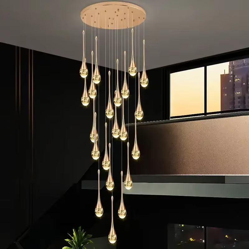 Modern gold long water drop chandelier with stainless steel and crystal teardrop LED lights hanging in a room